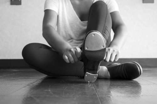 Tap dancer sliding on her tap shoes in the dance studio during dance class with a bottom view of the taps